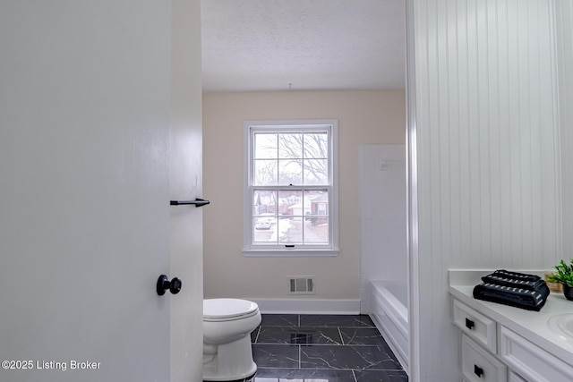 bathroom with vanity, toilet, and a textured ceiling