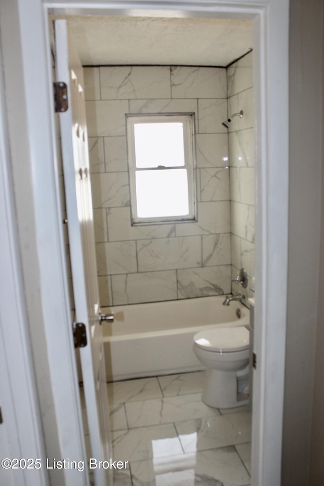 bathroom featuring tiled shower / bath and toilet