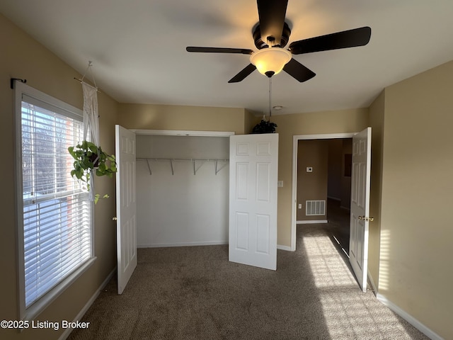 unfurnished bedroom with ceiling fan, a closet, and dark colored carpet