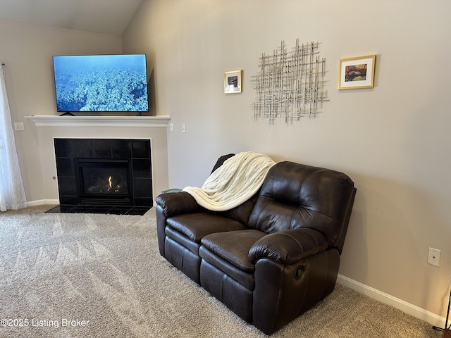 living room with carpet floors, a tiled fireplace, and vaulted ceiling