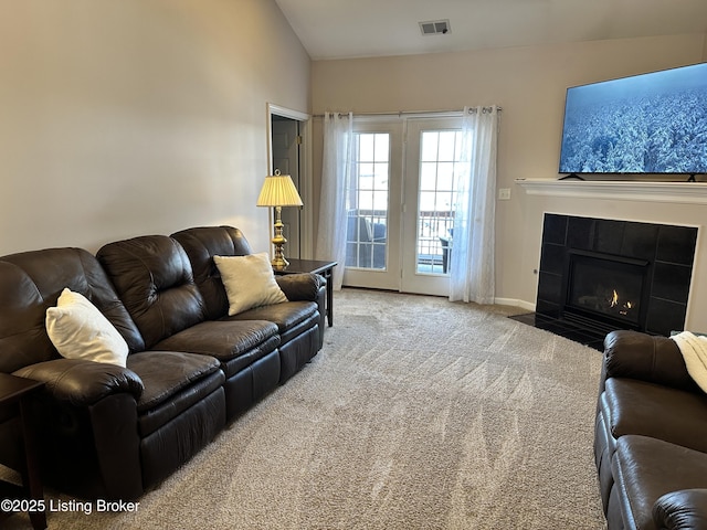 carpeted living room with a tile fireplace and lofted ceiling