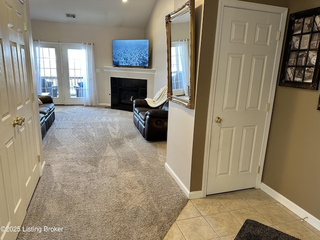 living room with lofted ceiling, light carpet, and a tiled fireplace