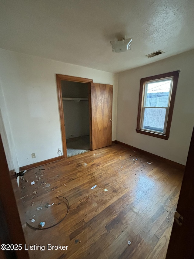 unfurnished bedroom with hardwood / wood-style floors, a closet, and a textured ceiling