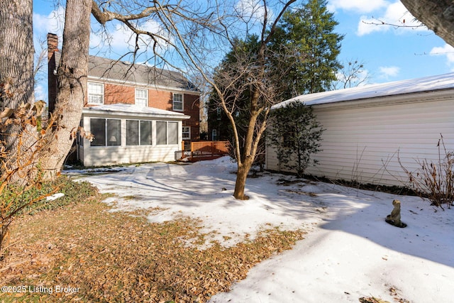 snowy yard featuring a sunroom