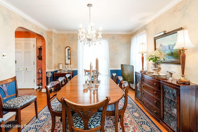 dining space with an inviting chandelier, crown molding, and light hardwood / wood-style floors