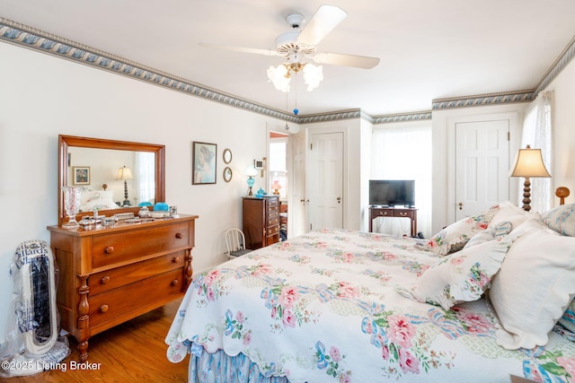 bedroom with crown molding, wood-type flooring, and ceiling fan