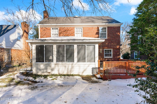 snow covered back of property featuring a sunroom and a deck