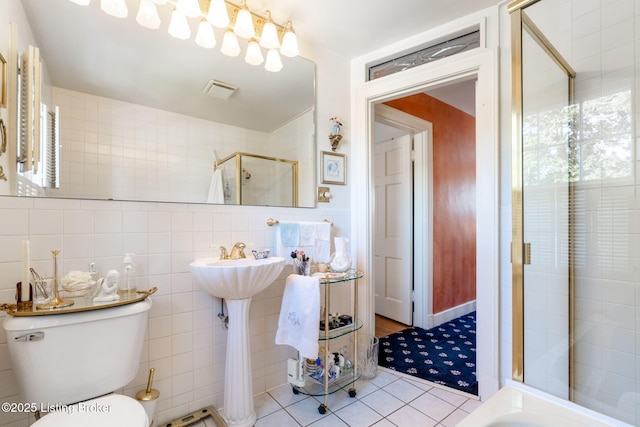 bathroom featuring toilet, a shower with shower door, tile patterned flooring, and tile walls