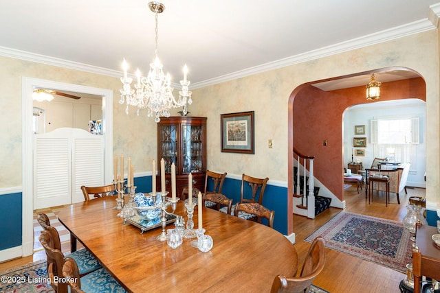 dining space featuring hardwood / wood-style flooring, crown molding, and ceiling fan with notable chandelier