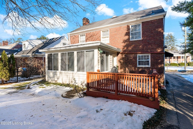 snow covered property featuring a deck and a sunroom