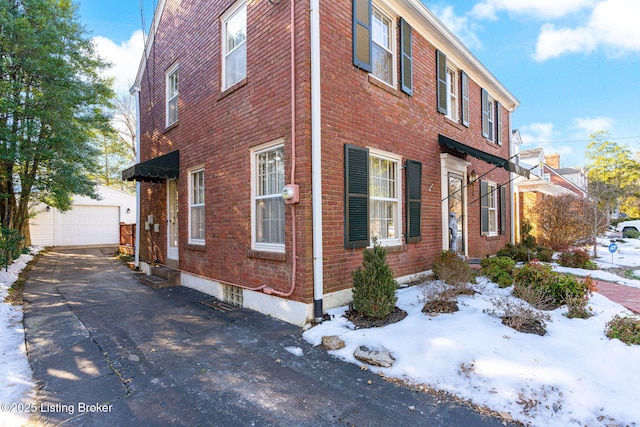 view of snowy exterior with a garage and an outdoor structure