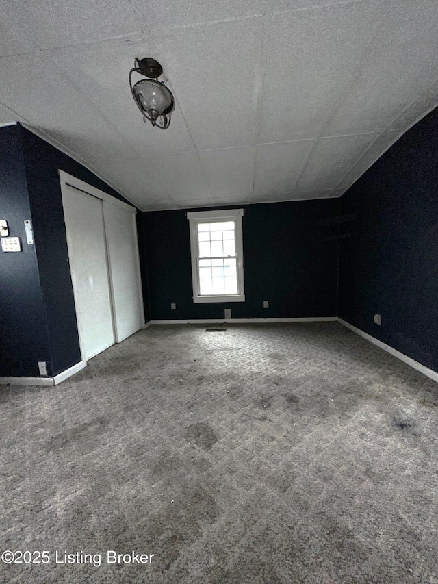 carpeted spare room with vaulted ceiling