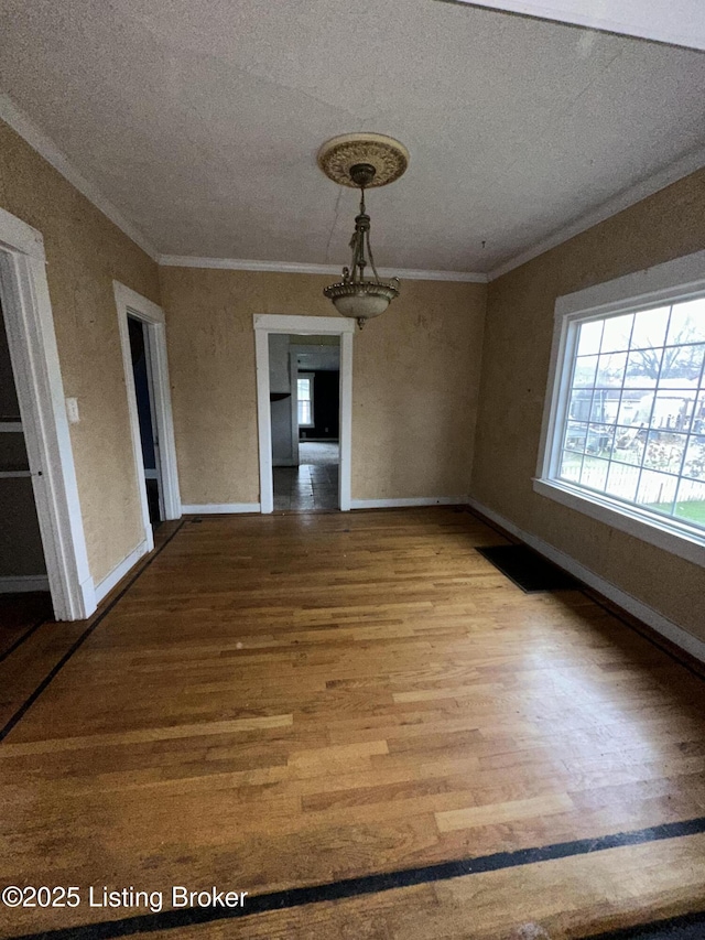 unfurnished dining area featuring hardwood / wood-style floors, a textured ceiling, and ornamental molding