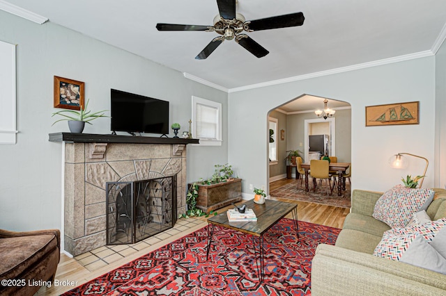 living room with a fireplace, hardwood / wood-style flooring, ceiling fan, and ornamental molding