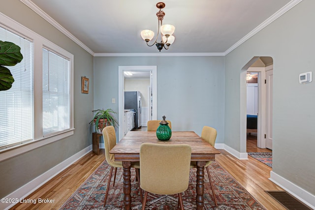 dining room with a chandelier, crown molding, and light hardwood / wood-style floors