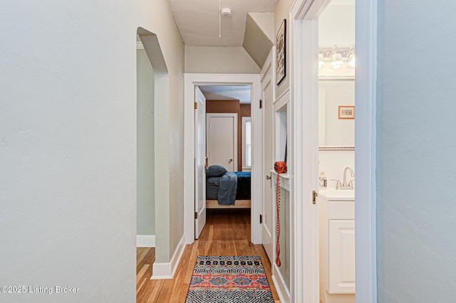 hallway with sink and light hardwood / wood-style flooring