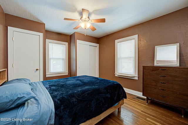 bedroom featuring wood-type flooring, multiple windows, a closet, and ceiling fan