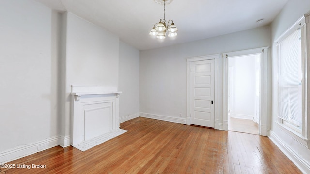 empty room featuring a chandelier and light hardwood / wood-style flooring