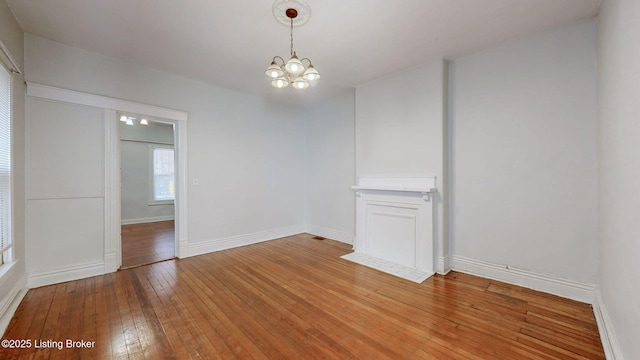 spare room featuring wood-type flooring and a chandelier