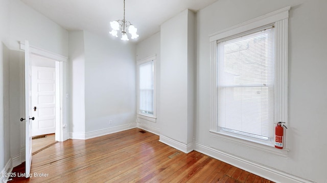 empty room featuring an inviting chandelier and light wood-type flooring