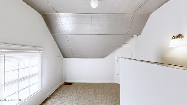 interior space with vaulted ceiling and light colored carpet