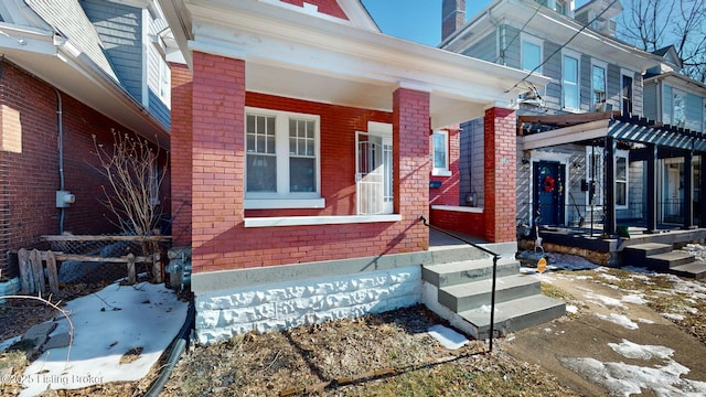 snow covered property entrance with covered porch