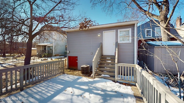 snow covered back of property with central AC