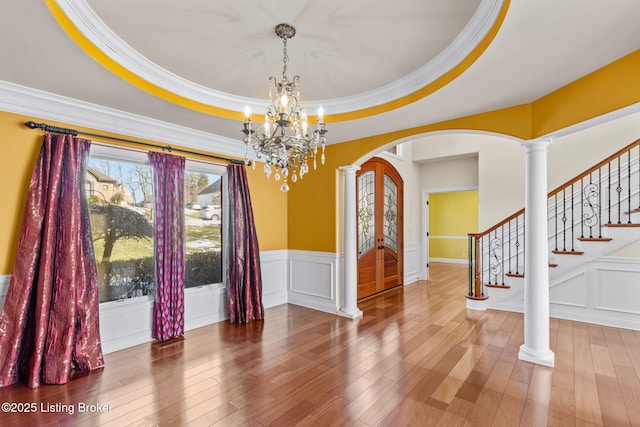 interior space featuring decorative columns, hardwood / wood-style flooring, a raised ceiling, and an inviting chandelier