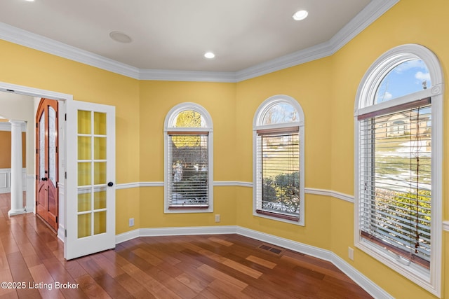 empty room featuring decorative columns, a healthy amount of sunlight, and ornamental molding