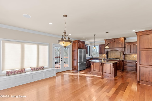 kitchen featuring pendant lighting, appliances with stainless steel finishes, a center island, light hardwood / wood-style floors, and a breakfast bar area