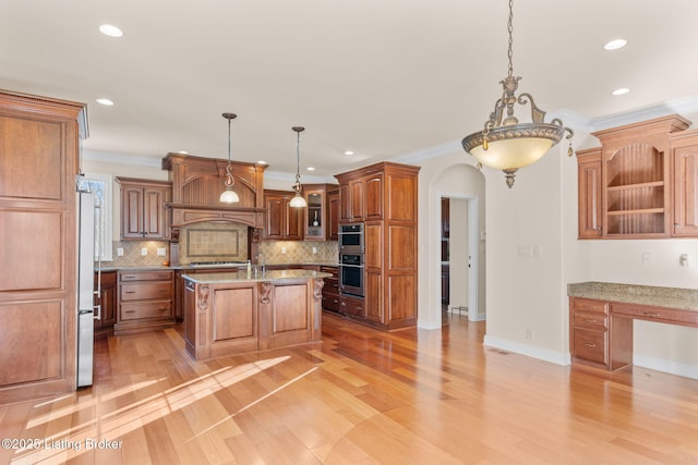 kitchen featuring decorative light fixtures, a center island with sink, and crown molding