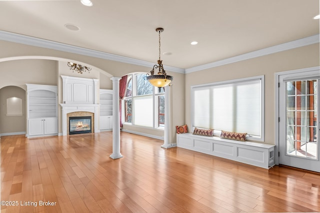 unfurnished living room featuring ornate columns, crown molding, and light hardwood / wood-style floors