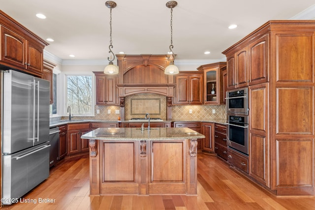 kitchen featuring pendant lighting, sink, light stone countertops, a center island with sink, and stainless steel appliances