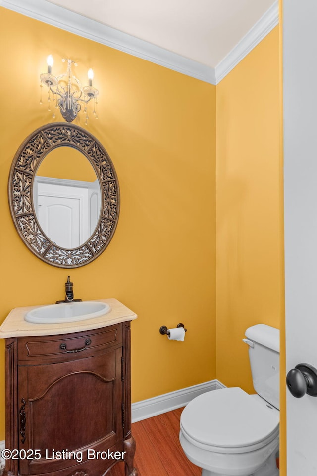 bathroom featuring hardwood / wood-style flooring, toilet, vanity, and ornamental molding