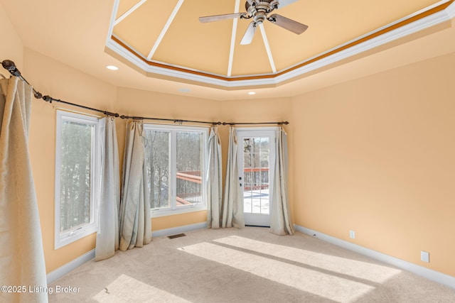 carpeted spare room with crown molding, ceiling fan, and a raised ceiling