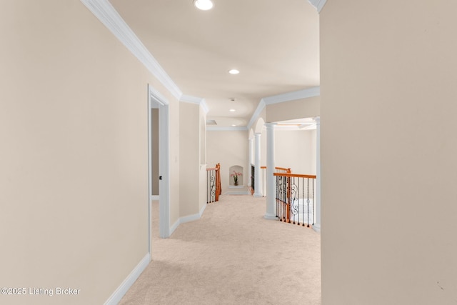 corridor with crown molding, decorative columns, and light colored carpet