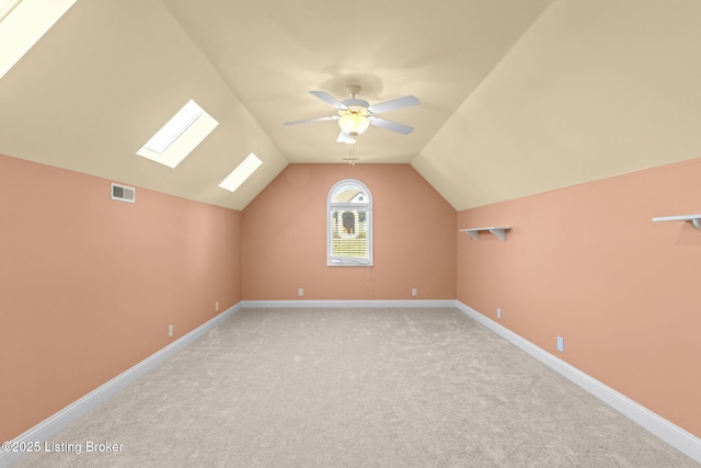 additional living space featuring ceiling fan, light carpet, and vaulted ceiling with skylight