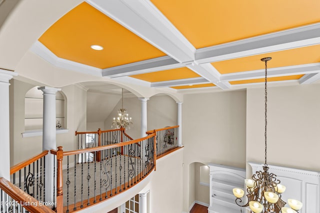 hall featuring beam ceiling, a notable chandelier, ornamental molding, coffered ceiling, and decorative columns