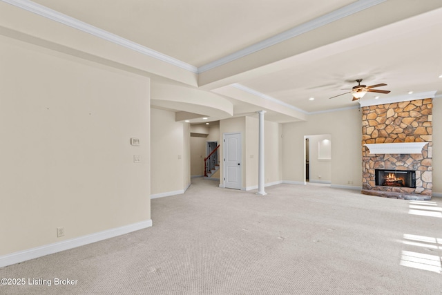 unfurnished living room with light carpet, ceiling fan, a stone fireplace, and ornamental molding