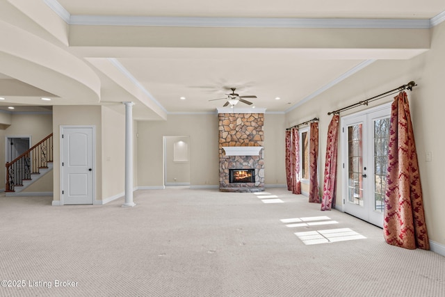 unfurnished living room featuring crown molding, ceiling fan, french doors, light colored carpet, and a stone fireplace