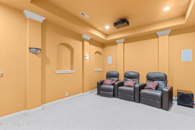 carpeted cinema featuring decorative columns and a tray ceiling