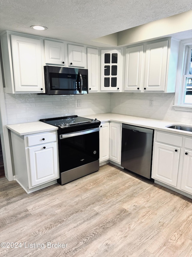 kitchen with black dishwasher, a textured ceiling, white cabinets, light wood-type flooring, and stainless steel electric stove