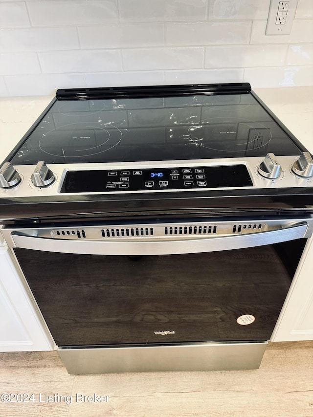 room details with white cabinets and stainless steel range with electric stovetop