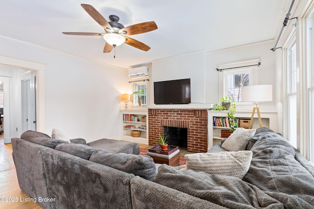 living room featuring ceiling fan, ornamental molding, a wall mounted AC, a brick fireplace, and light hardwood / wood-style flooring