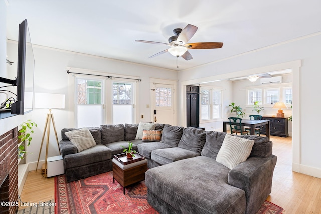 living room with crown molding, light wood-type flooring, a wall mounted air conditioner, and ceiling fan