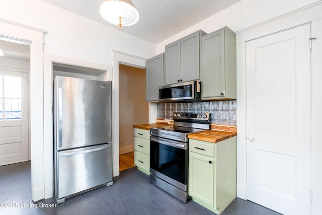 kitchen with backsplash, appliances with stainless steel finishes, green cabinetry, and wood counters