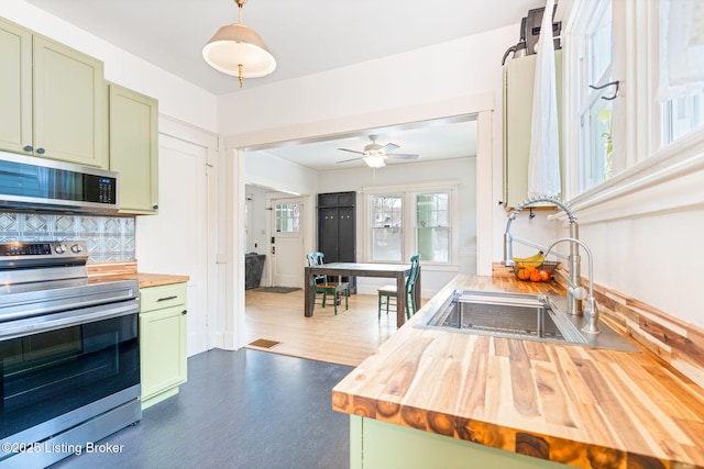 kitchen with sink, stainless steel appliances, green cabinetry, and butcher block countertops