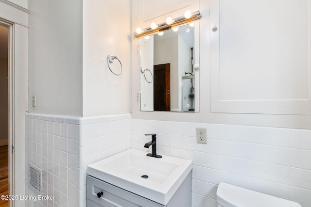 bathroom featuring vanity, toilet, and tile walls