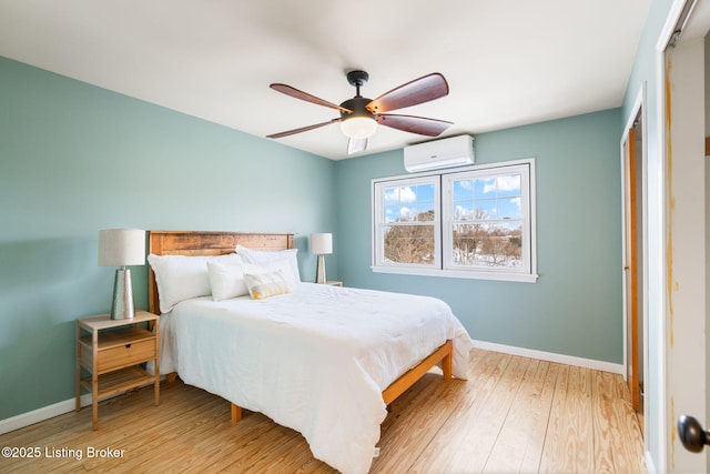 bedroom featuring light hardwood / wood-style flooring, a wall unit AC, and ceiling fan