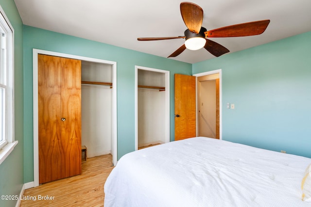 bedroom with ceiling fan, light wood-type flooring, and multiple closets